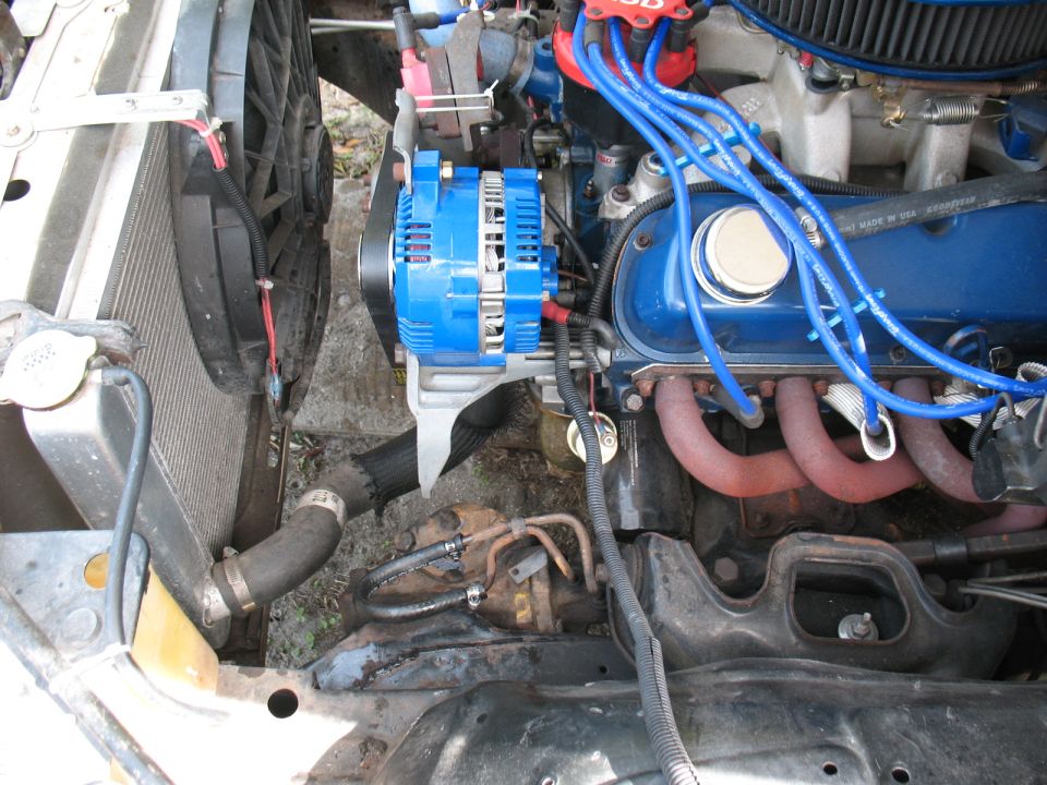 Engine bay showing a blue alternator, radiator fan, and exhaust manifold