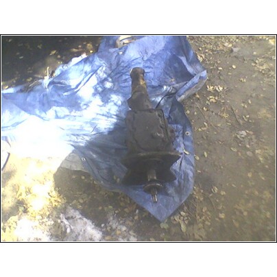 1972 Ford Ranchero - A greasy automotive suspension component rests on a blue tarp outdoors.