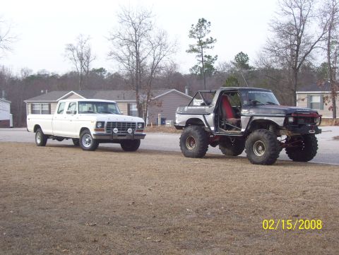 1978 Ford Bronco - A white Ford F-Series crew cab pickup truck and a heavily modified silver Ford Bronco are parked side-by-side.
