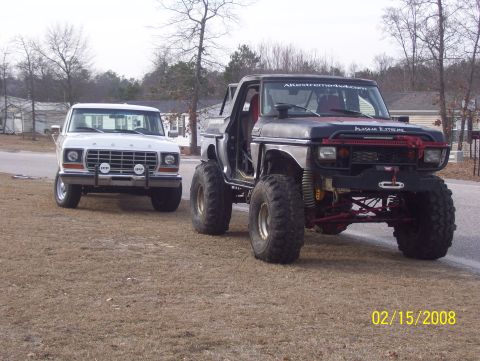 1978 Ford Bronco - Two square-body Ford 4x4s parked on a winter lawn beside a residential street, dated 02/15/2008. In the foreground is a heavily lifted door…