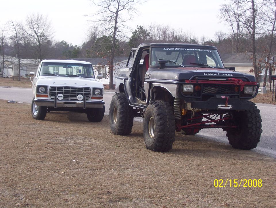 Lifted doorless black Bronco with winch bumper parked beside a white Ford pickup