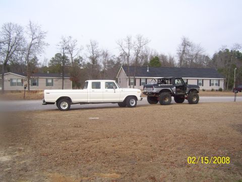 1978 Ford Bronco - A white crew cab truck tows a modified black Bronco on a dry, grassy lot with houses in the background.