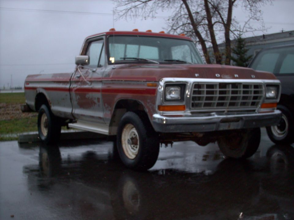 Red and silver Ford F-250 pickup truck from 1979, parked outside on a wet day