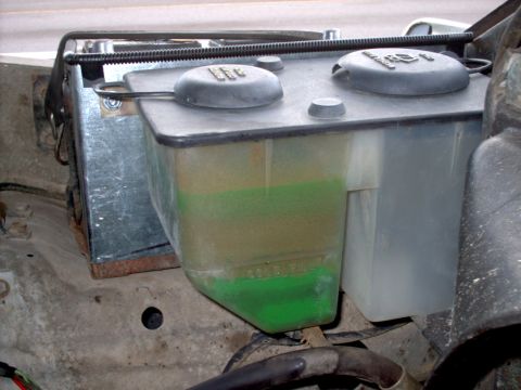 1979 Ford F-250 - The windshield washer fluid reservoir shows green fluid and a "FULL" marking, indicating its current level.