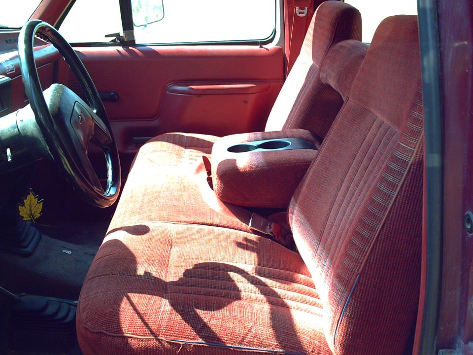 Red cloth interior of a 1991 Ford F-350 truck, showing the bench seat, steering wheel, and center console
