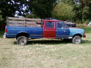 1991 Ford F-350 - This four-door pickup truck features a distinctive two-tone paint scheme and a custom wooden bed extension.