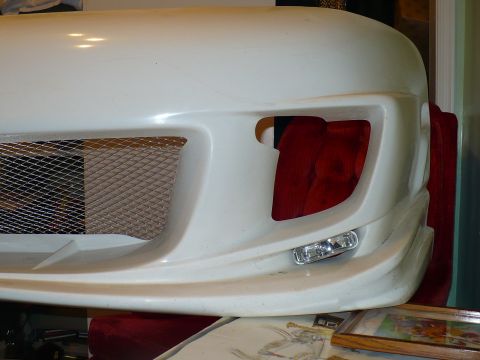 1993 Ford Probe - Close-up of a white aftermarket car bumper, a mesh grille and integrated fog light.