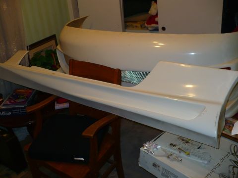 1993 Ford Probe - Unidentified white body kit parts, including a side skirt and bumper, are displayed indoors.