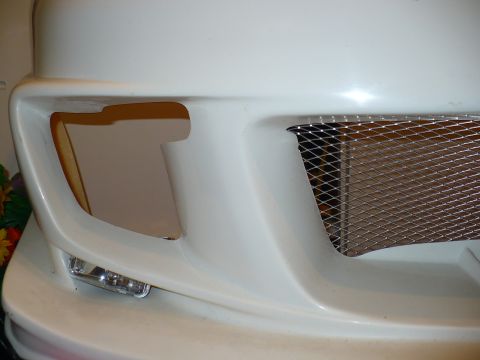 1993 Ford Probe - The front of a car with an aftermarket body kit is shown, a mesh grille and fog light housing.
