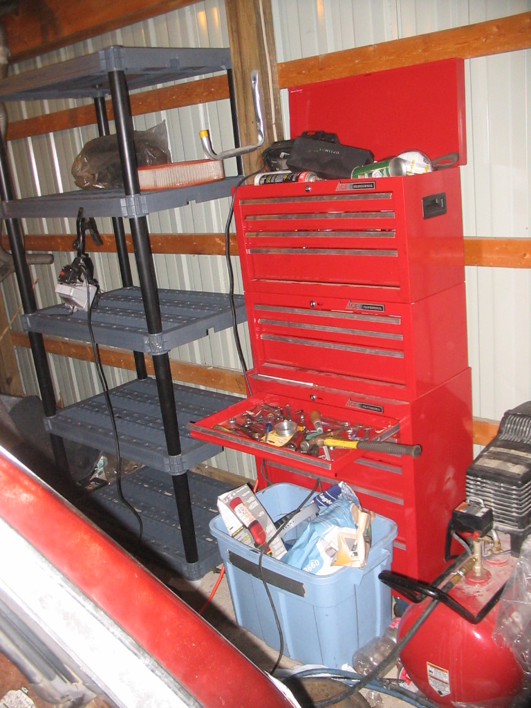 Took a break from getting greasy to clear out a very large pile of boxes from this side of the garage and replace them with this 1000-lb-capacity shelving unit from Lowe's.  Since another will fit alongside it very neatly between this post and the next one, my rollaway was moved from next to the workbench to its present location, and a more suitable spot was found for the air compressor as well.  You can't see in the pictures, but I recently replaced the petcock drain valve with some 1/4" galvanized pipe and a brass ball valve; draining the tank is now oh-so-much easier.  :2up: