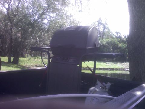 2001 Ford F-150 - A grill and propane tank are loaded into the bed of a truck, with a scenic outdoor background.