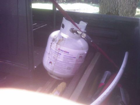 2001 Ford F-150 - Propane tank secured with a red strap in the bed of a pickup truck, with other items visible.