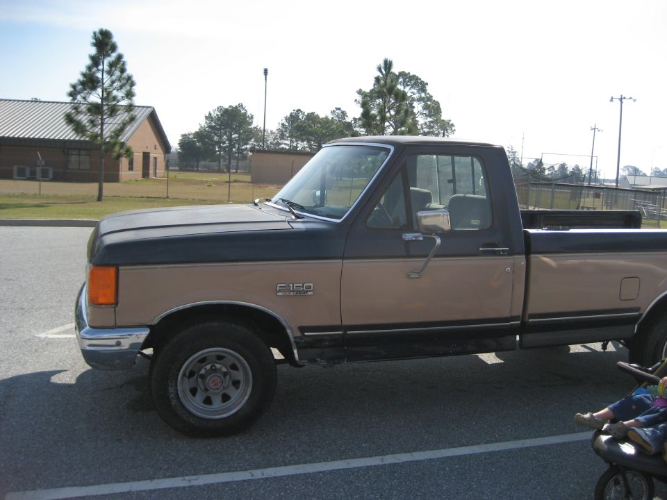 Two-tone tan and brown Ford F-150 regular cab long bed pickup, driver-side profile