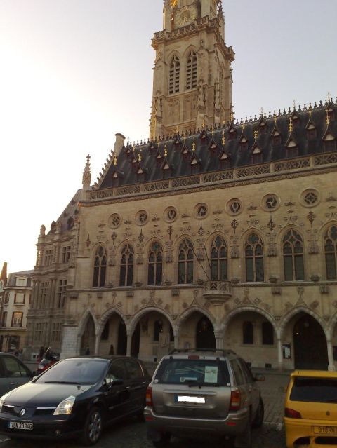 1991 Ford Crown Victoria - A silver SUV is parked in front of a large, ornate building with a prominent clock tower.