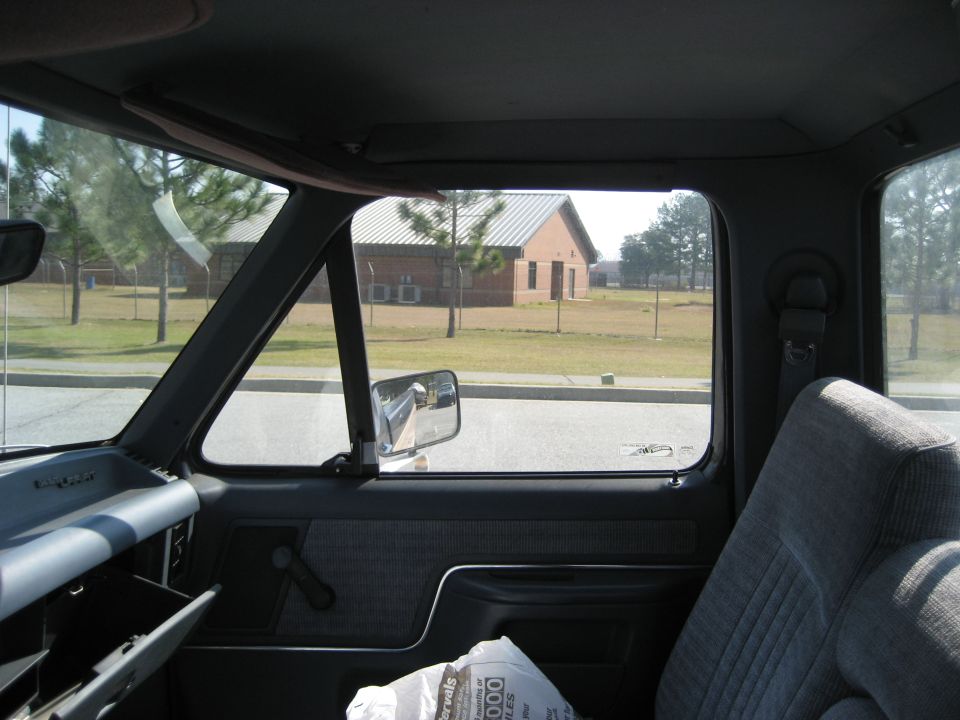 Truck interior showing dashboard, door panel, and seat, with a building visible through the window