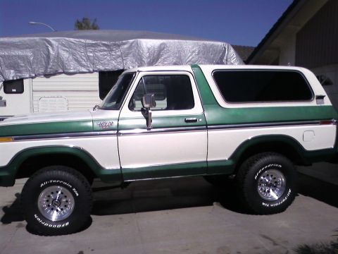1978 Ford Bronco - This two-tone Ford Bronco is parked in a driveway with a recreational vehicle behind it.