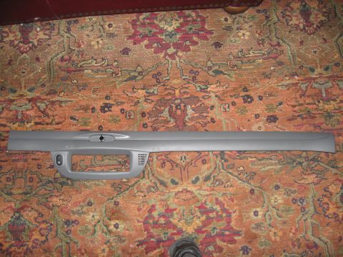 2004 Ford Crown Victoria - A gray dashboard trim piece, likely for a car's interior, is laid out on a patterned rug.