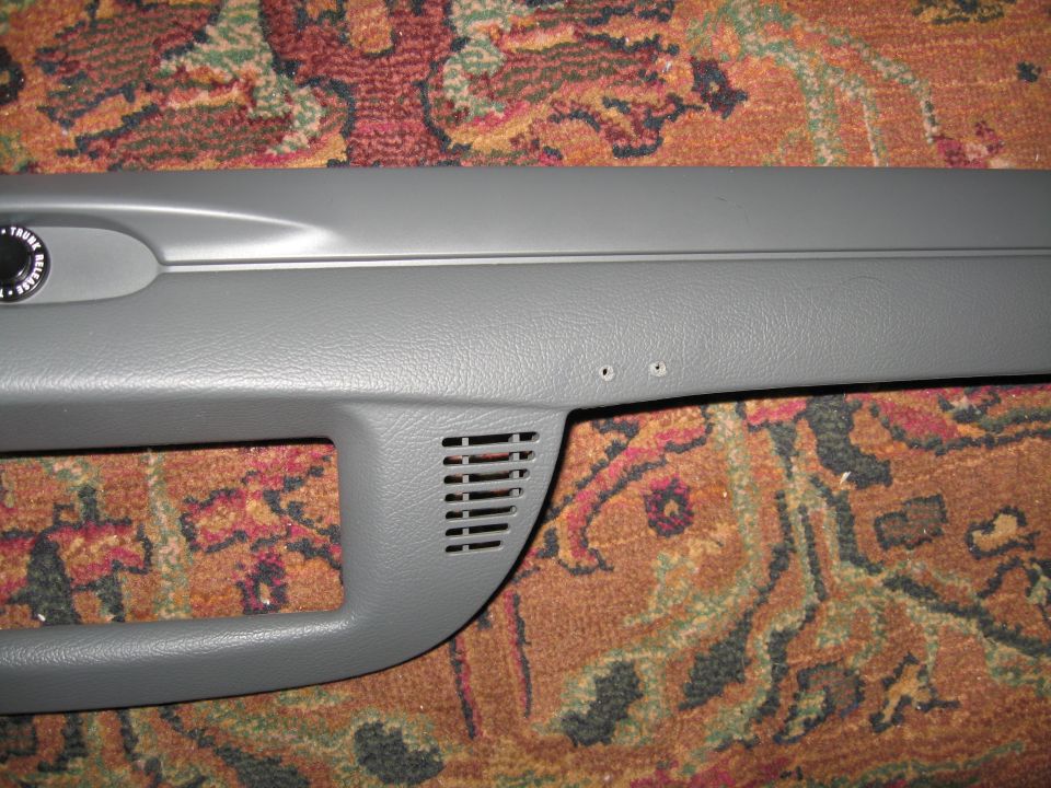 Close-up of gray plastic car interior trim with a vent and two screw holes