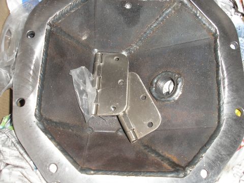 1995 Ford Bronco - A metal differential cover is shown with two attached hinges and some plastic wrapping. The registry claims it is a 1995 Ford Bronco part.