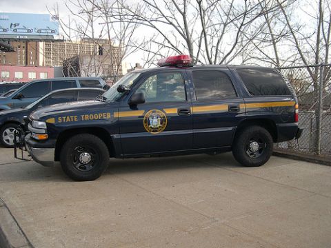 1991 Ford Crown Victoria - A dark blue police SUV with a yellow stripe and "STATE TROOPER" text is parked next to another vehicle.