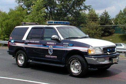 1991 Ford Crown Victoria - A dark blue and white police SUV with emergency lights is shown from the front-right side.