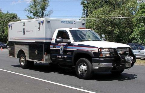 1991 Ford Crown Victoria - A Fairfax County police truck with a utility body drives on a road, with another police vehicle visible in the background.