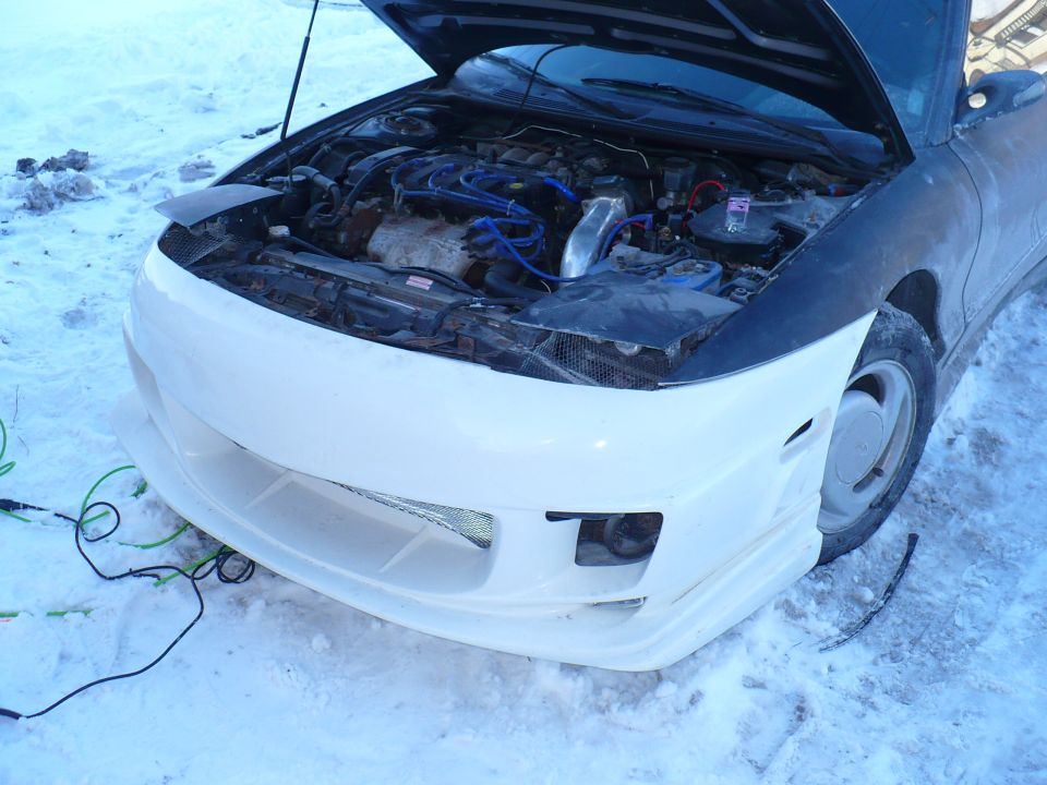 White custom front bumper on a dark car with hood open, parked in snow