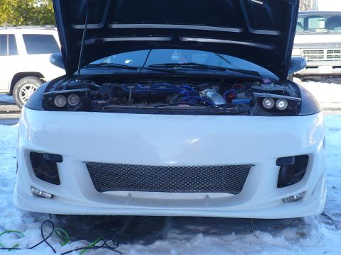 1993 Ford Probe - A white sports car with its hood open and a custom body kit is parked outside in the snow.