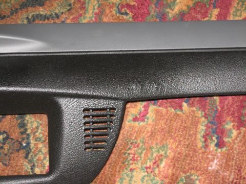 2004 Ford Crown Victoria - A close-up view of a car's interior dashboard trim piece, a small vent, is shown against a patterned carpet background.