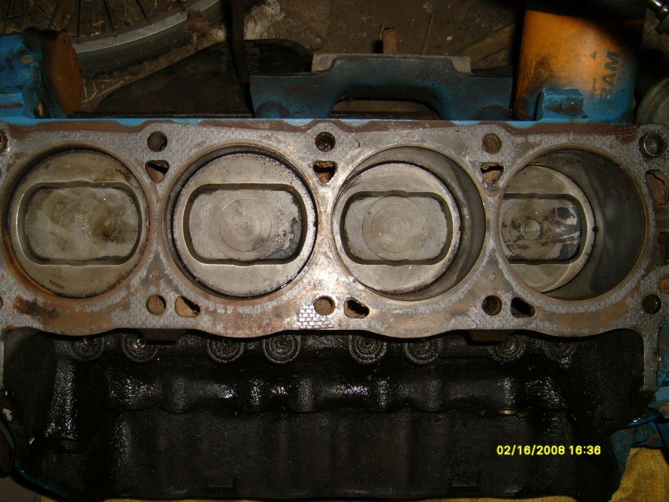 Engine block deck showing four pistons in their bores