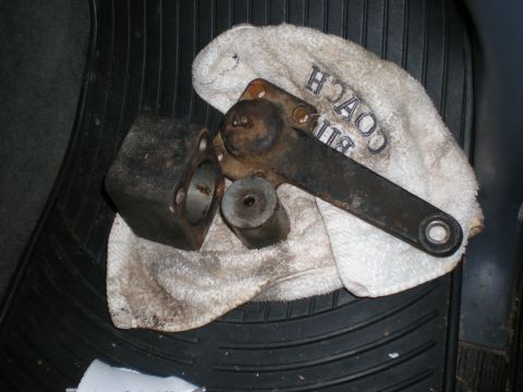 1993 Ford Bronco - Several metal automotive parts are laid out on a towel with text, resting on a vehicle's floor mat.