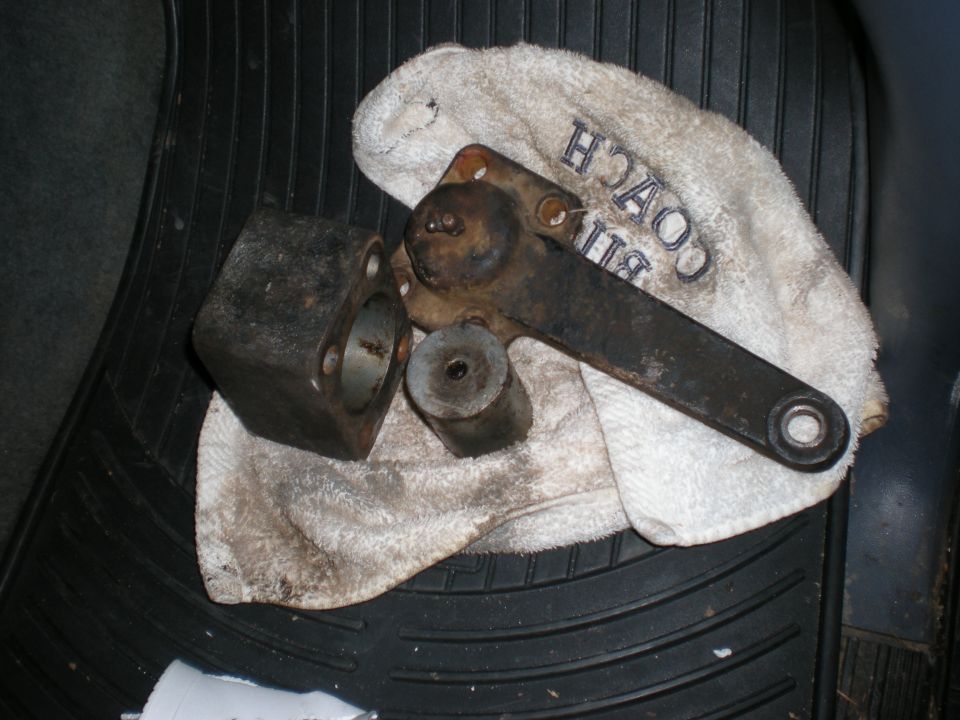 Metal automotive parts on a white towel with 'BILL COACH' text, on a black floor mat