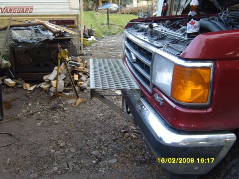 1989 Ford Bronco - Front view of a red pickup truck with its hood open, a metal platform attached to the bumper.