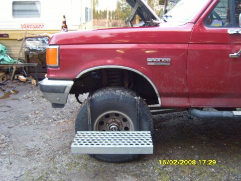1989 Ford Bronco - A red 1989 Ford Bronco is shown with its hood open and a custom metal step mounted to the front wheel.