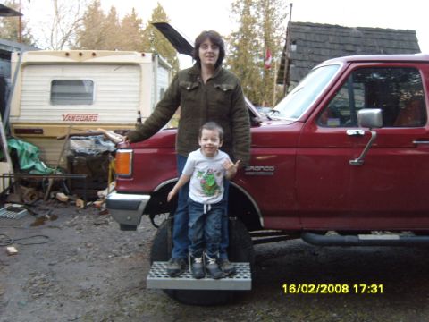 1989 Ford Bronco - A woman and a child pose in front of a red truck with its hood open.