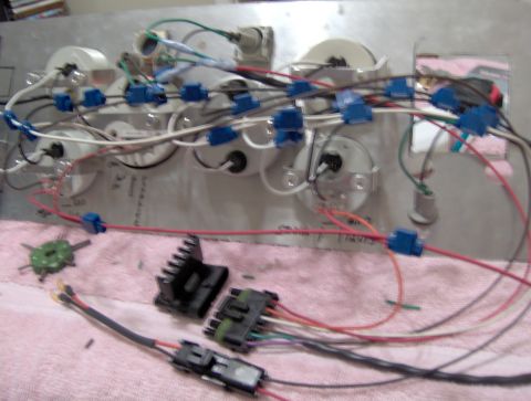 1978 Ford Bronco - A close-up view of a vehicle's dashboard wiring harness and gauges, numerous blue connectors and loose electrical wires.