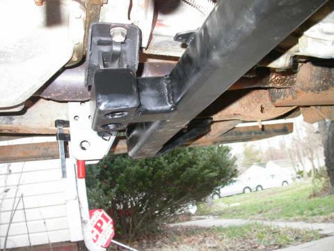 1990 Ford Bronco - Close-up view of an aftermarket bracket attached to the undercarriage of a vehicle. A sign with 'CPI' is visible.
