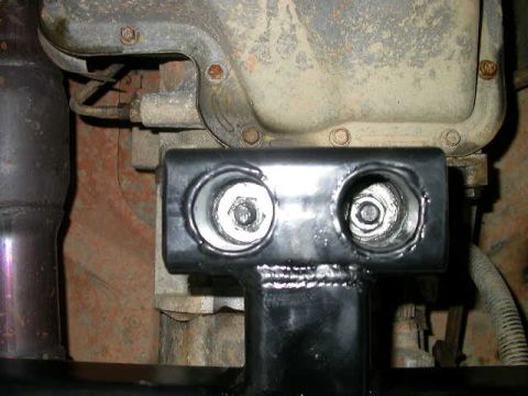 1990 Ford Bronco - Close-up of a vehicle's drivetrain component, possibly a transmission or transfer case, with a bracket attached.