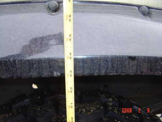 Tape measure held vertically against a dark blue vehicle body panel, measuring its height