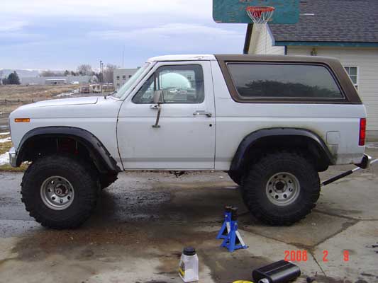White full-size 1980s Ford Bronco on jack stands in a driveway