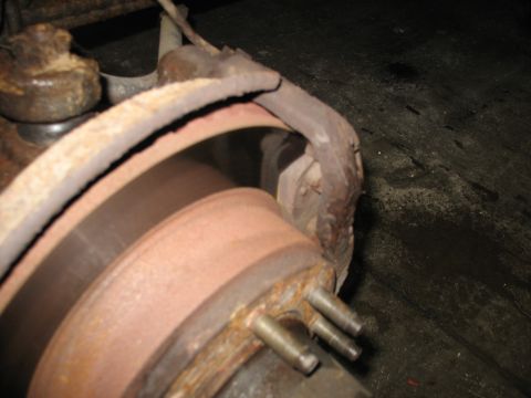 1995 Ford C-350 (Centurion Conversions) - Close-up view of a heavily rusted brake rotor and caliper assembly.