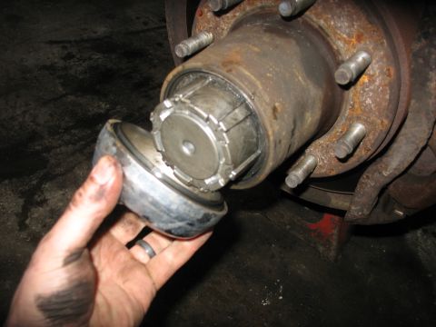 1995 Ford C-350 (Centurion Conversions) - Close-up of a vehicle's front wheel hub assembly with a cap being removed, revealing internal splines.