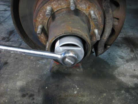 1995 Ford C-350 (Centurion Conversions) - A socket wrench is used to turn a nut on a vehicle's wheel hub.