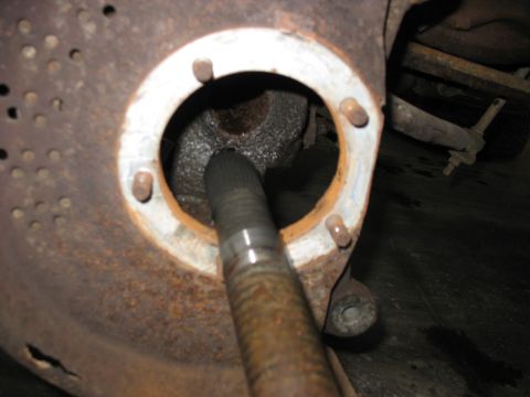 1995 Ford C-350 (Centurion Conversions) - Close-up of a splined axle shaft inserted into a rusty hub assembly, likely part of a front axle rebuild.