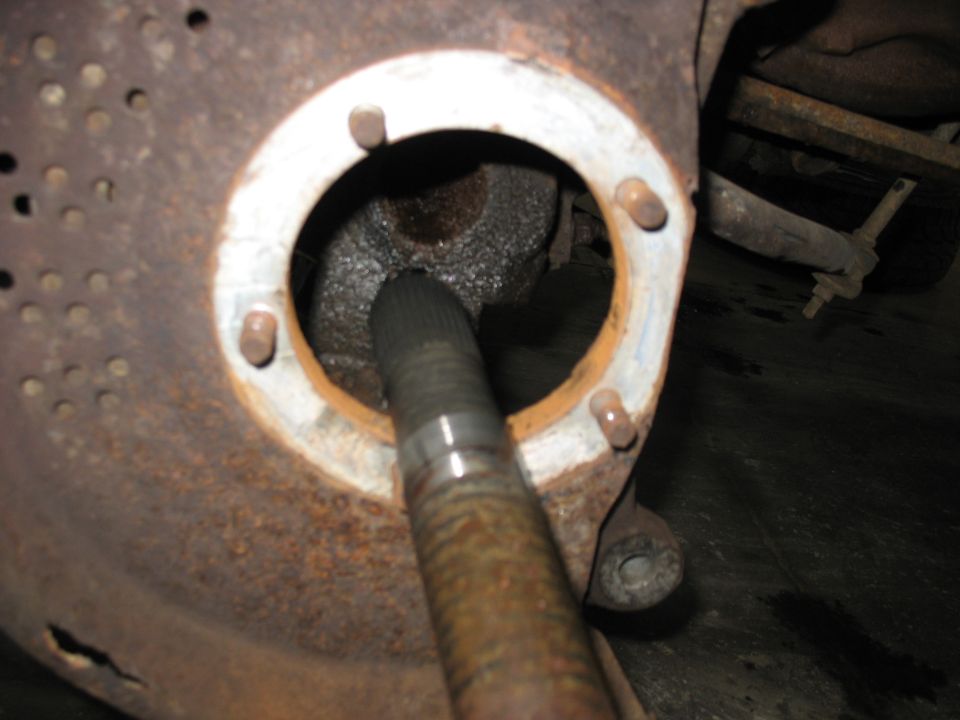 Close-up of a splined axle shaft inserted into a rusty hub assembly