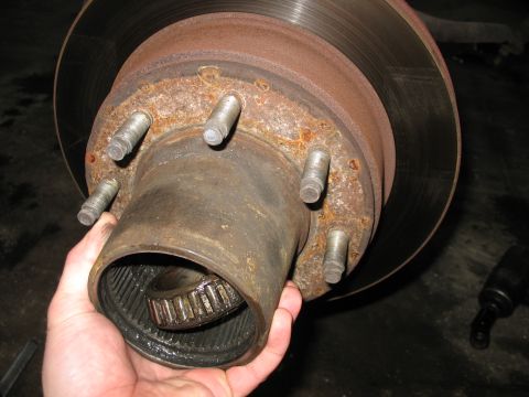 1995 Ford C-350 (Centurion Conversions) - Close-up of a rusty front axle hub assembly, showing the bearing and brake rotor, likely during a rebuild.