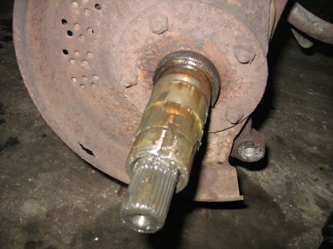 1995 Ford C-350 (Centurion Conversions) - Close-up of a rusted axle shaft and brake rotor, likely from a vehicle undergoing front axle work.