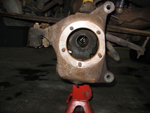 1995 Ford C-350 (Centurion Conversions) - Close-up of a vehicle's front wheel hub assembly, supported by a red jack stand.
