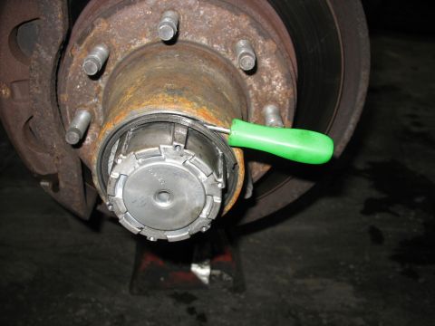 1995 Ford C-350 (Centurion Conversions) - Front wheel hub assembly detail with a tool being used on the locking mechanism.