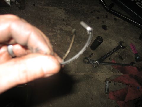 1995 Ford C-350 (Centurion Conversions) - Mechanic holding a metal clip with tools laid out on the floor during a repair.